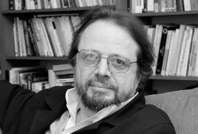 A autobiografia é um gênero que sempre provoca reflexões sobre questões de identidade autor/narrador, e as relações que se estabelecem entre leitor e autor; isso para não falarmos de questões como tipos de autobiografia e das fronteiras entre ficção e realidade. Há inúmeras variáveis a se considerar e demonstro aqui com uma breve relação nada completa: O romance Dom Casmurro, que se apresenta como autobiografia; Cerimônia de adeus, memórias de Simone de Beauvoir, que conta a história de um outro, o triste final de Sartre; Quarto de despejo, de Carolina Maria de Jesus, em que o texto autobiográfico da favelada surge avalizado e editado por uma terceira pessoa, jornalista. Memórias, autobiografias e diários são subgêneros que, por sua vez, problematizam ainda mais esse tipo de escrita. Cristovão Tezza, em O filho eterno, escreve uma autobiografia problematizada pela narrativa em terceira pessoa num gênero que, por muito tempo, foi o feudo da primeira pessoa.O livro tem duas epígrafes que servem para orientar os leitores na abordagem do texto. A primeira, de Thomas Bernhard, questiona o quesito “verdade” (“o descrito é outra coisa que não a verdade”). O quanto de verdade se pode encontrar num texto, escrito por alguém que já não é mais aquele que viveu os fatos narrados? Ao utilizar-se da linguagem verbal, intermediária que necessita da lógica para sua organização, e ao se colocar na posição de narrador, o autor se afasta dos episódios e os analisa e rearranja, mesmo não sendo essa sua intenção. E, os que lêem o texto “na dor lida sentem bem não as duas que ele teve, mas a que ele não tem” (Fernando Pessoa, citado de memória). Assim sendo, nos afastamos cada vez mais da origem, do acontecimento narrado, na impossibilidade de fazer do texto a própria vida.A problematização da verdade na narrativa autobiográfica parece datar do surgimento das Confissões de Rousseau. Os textos autobiográficos, antes do autor suíço, se preocupavam em fazer relatos de episódios de vida que engrandecessem ou justificassem os atos passados de seus narradores. Rousseau modifica essa atitude com a proposta de “dizer tudo”, e contar os episódios todos de sua vida, mesmo os mais sórdidos, como o abandono dos filhos. Por maior que seja o desejo de contar tudo, sempre algo precisará ficar de fora. As motivações são sempre múltiplas e por mais que se esmiúcem os detalhes, alguns escaparão. Há toda espécie de “traição”: esquecimento, falta de percepção, mudança de atitude, e a mera impossibilidade física de narrar uma vida como vai acontecendo por razão de transformar a obra em texto ilegível e desconexo. “Em Rousseau, a escrita do je (o eu) se encontra com o jeu (o jogo) da escritura. E com ele se abre, para a modernidade, o paradigma das articulações infinitesimais da identidade, do sujeito e da subjetividade” (Lúcia Helena).Nesse jogo da escritura, Cristovão Tezza acrescenta uma variável incômoda: a terceira pessoa num texto confessadamente autobiográfico. Qual atitude tomar perante um narrador que, de antemão, reconhece que o protagonista de sua autobiografia não é, nem pode ser ele mesmo, pois os fatos narrados aconteceram com alguém que já não existe mais, ou com alguém que passa a se definir em relação a um outro? Conforme nos ensina a professora Myriam Ávila, a “autobiografia compartilha questões de base com a filosofia, tais como a do conhecimento de si e a convergência possível entre verdade e expressão, configurando-se como um cruzamento inevitável entre aquela disciplina e a literatura”.DúvidaVoltamos, assim, às epígrafes do livro, já que a segunda delas, de Kierkegaard, esclarece que pai e filho têm uma relação especular que se resolve no tempo: um olha para o outro e ambos se vêem em momentos diferentes da vida. Há um desdobramento analítico que não nos cabe fazer, mas que é passível de especulação, aproveitando o tema semântico — o jovem imaturo e sonhador que recebe um filho que não poderá duplicar, nem replicar, seu lado adulto e intelectualizado, mas que revelará uma faceta mal resolvida do jovem órfão, do jovem sem pai, condenado, por isso, a uma falta de modelo adulto. Pergunta-se, então: quem é, em última análise, esse filho eterno? Felipe ou seu pai?O texto começa com o nascimento do bebê. A mulher avisa que chegou a hora e começa, então, o percurso do texto. Lemos: “em matéria de novidade, amanhã ele seria tão novo quanto o filho”. Ambos, então, estão juntos nesta viagem de conhecimento. Pai e filho estabelecem uma relação de complementaridade, um só o é por causa do outro. Nas idas e vindas da narrativa, lemos as memórias de uma outra era, de alguém que vivia apenas de futuro, que era uma promessa e se percebia com um papel a desempenhar: “só a expectativa de um futuro vago e mal desenhado”, diz o narrador, numa frase que se torna ambiguamente referente ao filho e ao pai, nascentes. Quando, ao final do primeiro capítulo, o médico chega para informar o nascimento, é saudado com um sonhador:— Tudo bem? — ele pergunta, por perguntar: a cabeça já está no mês seguinte, sete meses depois, um ano e três meses, cinco anos à frente, o filho crescendo, a cara dele.A esse pai alojado no futuro, no entanto, cabe um filho que viverá eternamente no presente (“O tempo será sempre um presente absoluto.”)As histórias vão se desenrolando paralelas: o filho, instado para tornar-se “normal”, rejeitado a princípio, vai adquirindo uma identidade própria dentro de suas limitações. Se o primeiro vínculo entre pai e filho é tênue — o incessante colocar do dedo na palma da mão da criança, a fim de que esta cerre os dedinhos em torno deste dedo (o consolo de existir pelo menos esse tipo de reação “normal”) —, e se a rejeição é um dado importante, a ser domesticado, pouco a pouco se observa o surgimento de certa simpatia. A criança rejeitada vai conquistando seu lugar, penosamente. Na vitória do filho, o que se enxerga, porém, é o fracasso do pai. No episódio em que se narram os esforços da criança para subir, sem ajuda, no banco do motorista, lemos a crise de alguém que se reconhece no outro — “Pai e filho são parecidos, espelham-se naquele instante violento e absurdo”. Este, que parece o momento mais terrível, aquele de maior afastamento entre criança e adulto é também o momento em que se igualam, em que mais se assemelham, presos a síndromes diferentes, mas que os impedem de sair da infância eterna. Narrar esse episódio cheio de pathos é o primeiro passo deste Adão que tenta organizar seu mundo: Dar nome às coisas. Escrever é dar nome às coisas. Ele não pode dizer: dar nome às coisas tais como elas são — porque as coisas não são nada até que digamos o que elas são. Que coisa é meu filho?É com clareza que o autor examina e revela o passado. De fora, tempos depois, longe já do olho do furacão que o arrasta à violência e ao abandono, ele contempla e nomeia o que por muito tempo ficou inominável. Abjurando as teorias de Rousseau, é o momento que mais se aproxima da confissão em si, em que pratica o “dizer tudo”, e em que revela sua humanidade: “A natureza não tem alma alguma, e, deixados à solta, seremos todos pequenos e grandes monstros”. Mas o autor não deixa o texto à solta, bem como o pai não abandona o filho, o de ontem e o de agora. As crises ainda se sucedem, mas a aceitação germina, desde os primeiros contatos. A teimosia pode ser lida como tenacidade, e são esses esforços perseverantes que vão resgatando esse filho. O pai “cientista” e o pai “esperançoso” encontram o pai “amoroso”, mas o desenvolvimento é lento e penoso. Somente crises provocam avanços, e é na crise do desaparecimento da criança que sua união se solidifica. Para espanto de quem já pensara em abandonar a criança imperfeita (“o mesmo filho que ele desejou morto assim que nasceu, e que agora, pela ausência, parece matá-lo”) os termos de ternura se infiltram no texto, mesmo falando com crueza científica sobre as limitações do filho e sobre as próprias incapacidades. O texto se suaviza, cada vez mais consciente. Purgando-se das culpas, finalmente amadurecendo, o narrador se reconcilia com seu eterno passado e o eterno presente do filho. E, nesse processo, a escrita foi fundamental, por ter-lhe permitido descobertas, inclusive a mais importante: vida e escrita são distintas, não devem ser confundidas e precisam “manter uma relação respeitosa e não muito íntima”.Com o penoso retirar das máscaras, e uma reinterpretação do pacto autobiográfico, Tezza elabora, com perícia magistral, uma biografia a ser compartilhada entre pai e filho. E, mesmo que a palavra não seja dita, o sentimento de amor aflora e emociona.O AUTOR:Cristovão Tezza nasceu em Lages (SC), em 1952, mas mudou-se para Curitiba ainda criança. Além de escritor, com mais de uma dezena de livros publicados, leciona na UFPR. É autor, entre outros, de Trapo, O fantasma da infância, Aventuras provisórias, Breve espaço entre cor e sombra, O fotógrafo e O filho eterno.Trecho • O filho eternoEm uma das peças da comunidade, nos anos 1970, como aquela que foi ao palco em São Paulo, o pai representava um mendigo que havia matado a mãe e se confessava num certo Templo das Sete Confissões, em plena Idade Média. Era uma espécie de teatro-verdade, um texto que se foi construindo em improvisos emocionais e emocionados, cada ator criando boa parte de suas falas até o conjunto final ser lapidado pela mão férrea da direção. Havia um pouco de tudo na concepção do projeto, cacos de Jung a Freud, passando por exercícios de humilhação e entrega, sob a sombra de um certo cristianismo medieval impregnado de uma inescapável volúpia da culpa. Cada ensaio era uma sessão quase religiosa — no limite, chegava às vezes a uma verdadeira contrição de penitentes. Na visão do diretor, a concentração não deveria ser a mera expressão de uma técnica, um exercício de autocontrole; deveria ser antes uma fusão com alguma voz verdadeira da alma. A utopia do “sentimento verdadeiro” estava no ar: todos buscavam a “verdade das emoções”, o grito primal, a realidade supostamente bruta e incontrolável dos arquétipos, e nessa busca a fronteira entre o mundo estético e o mundo da vida não tinha nenhuma nitidez.